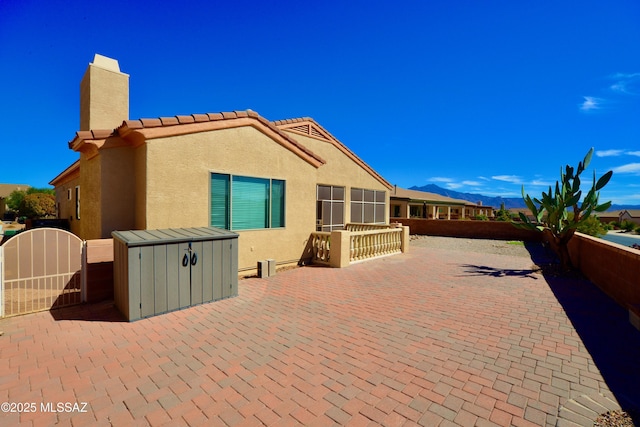 exterior space with a patio, a chimney, stucco siding, a gate, and fence