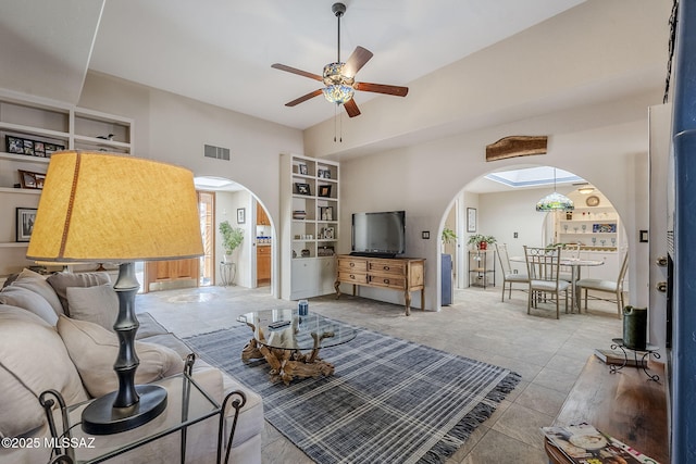 living area with visible vents, built in shelves, arched walkways, and ceiling fan