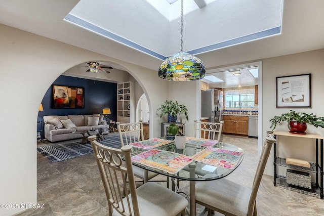 dining space featuring arched walkways, ceiling fan, and built in features