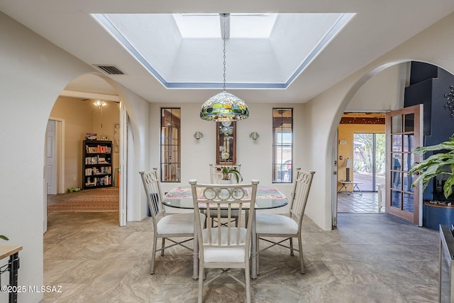 dining space with visible vents, arched walkways, and a raised ceiling