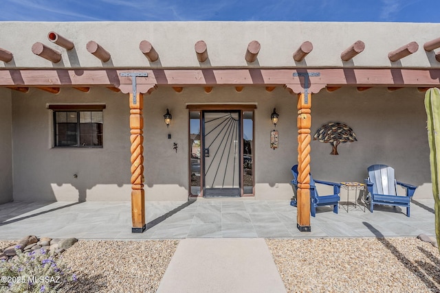 entrance to property featuring a patio and stucco siding