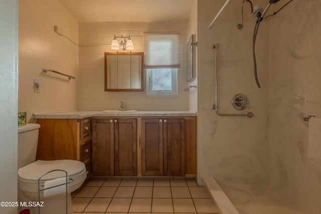 bathroom with tiled shower, tile patterned floors, toilet, and vanity