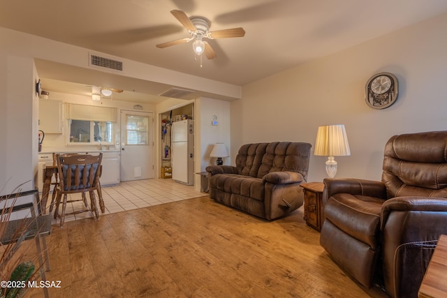 living room featuring sink, light hardwood / wood-style floors, and ceiling fan