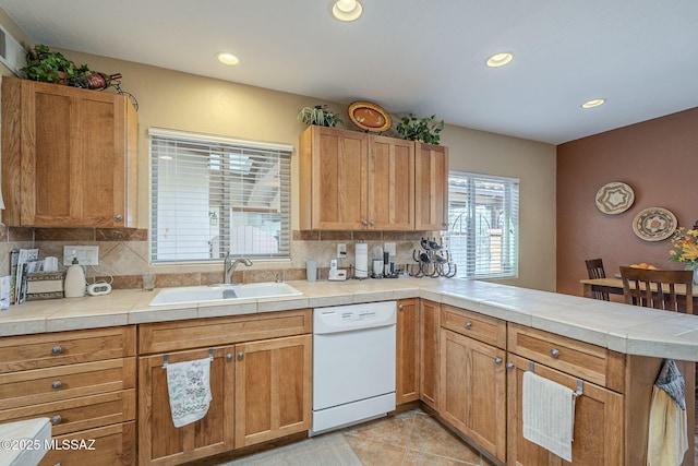 kitchen featuring kitchen peninsula, white dishwasher, tasteful backsplash, and sink