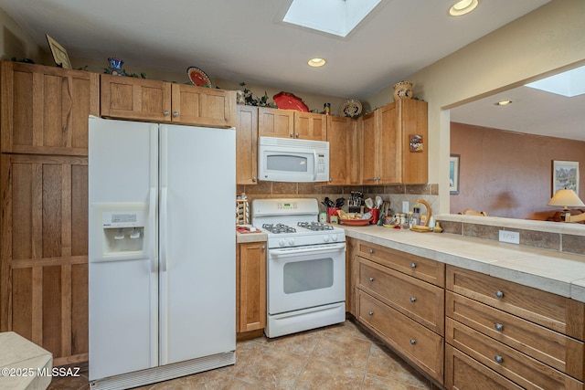 kitchen featuring backsplash, white appliances, and a skylight