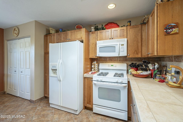 kitchen featuring white appliances, light tile patterned floors, tile countertops, and decorative backsplash