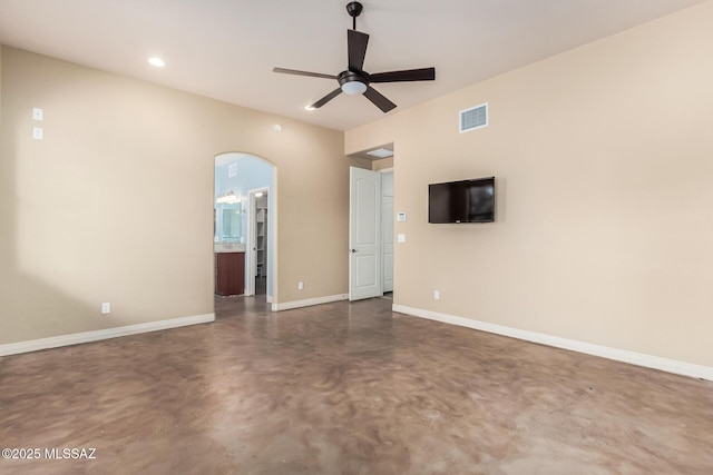 empty room with baseboards, visible vents, arched walkways, ceiling fan, and finished concrete floors