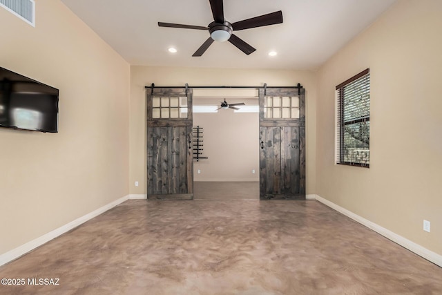 spare room featuring a barn door, finished concrete floors, and baseboards