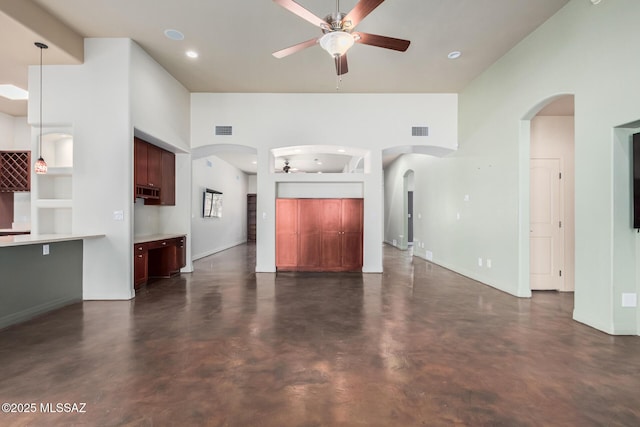 unfurnished living room featuring a ceiling fan, arched walkways, visible vents, and concrete flooring