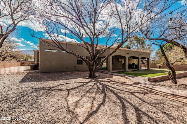 rear view of house featuring cooling unit, a patio area, fence, and stucco siding