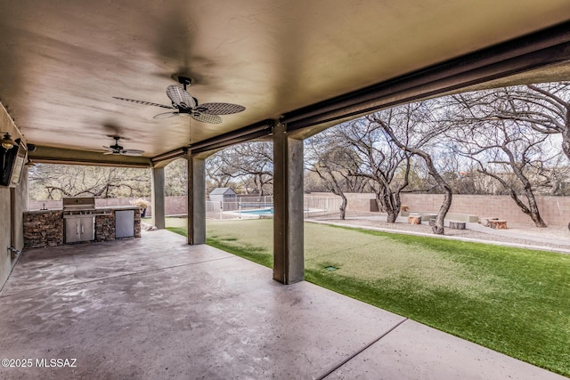 view of patio featuring an outdoor kitchen, area for grilling, ceiling fan, a fenced backyard, and an outdoor structure