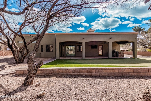 rear view of house featuring a chimney, stucco siding, a lawn, a ceiling fan, and a patio area