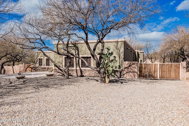 view of front of house with a gate, fence, and stucco siding