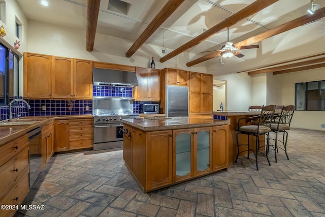 kitchen featuring sink, a breakfast bar area, decorative backsplash, high end appliances, and wall chimney exhaust hood