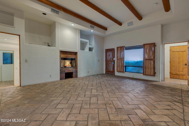 unfurnished living room with a fireplace, beamed ceiling, and a high ceiling