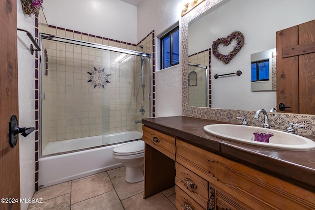 full bathroom with vanity, combined bath / shower with glass door, tile patterned floors, and toilet