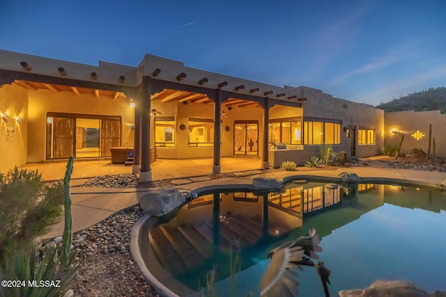 back house at dusk featuring a patio