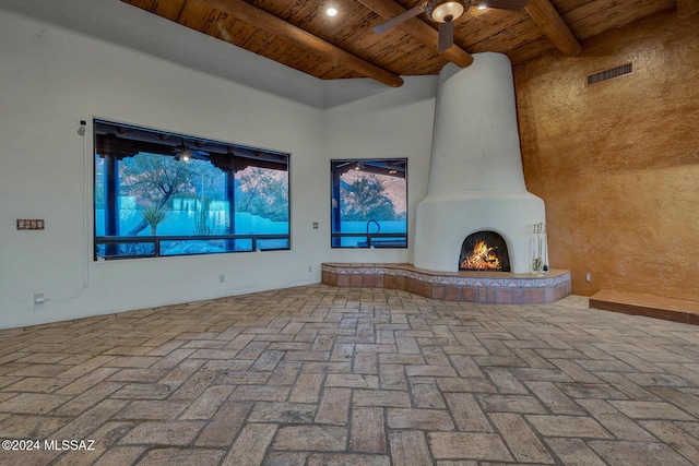 unfurnished living room featuring wood ceiling, ceiling fan, and beam ceiling