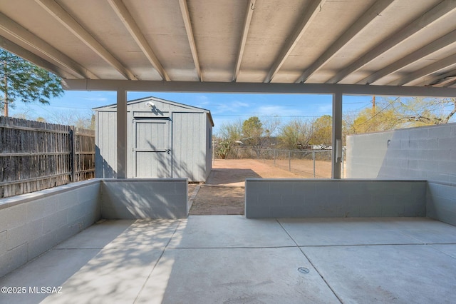 view of patio / terrace with an outbuilding, a fenced backyard, and a shed