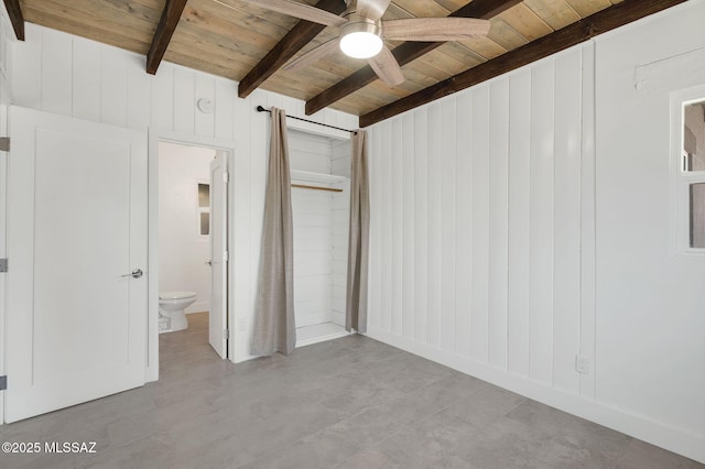 unfurnished bedroom with wooden walls, wood ceiling, ensuite bath, and beam ceiling