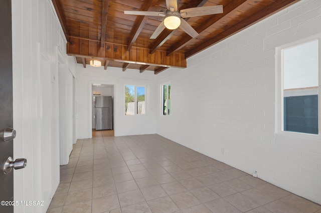 empty room with beam ceiling, a ceiling fan, wood ceiling, light tile patterned flooring, and brick wall