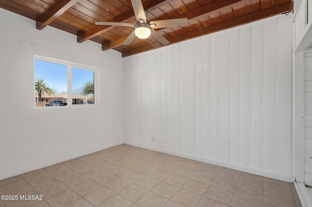 unfurnished room with beam ceiling, a ceiling fan, light tile patterned flooring, brick wall, and wooden ceiling