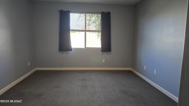 unfurnished room featuring baseboards and dark colored carpet