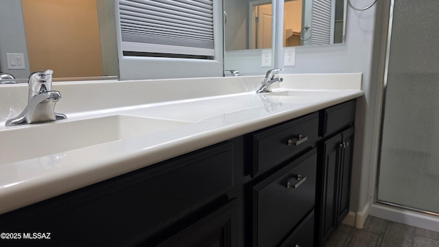 bathroom featuring radiator, a shower stall, wood finished floors, a sink, and double vanity