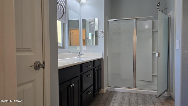 bathroom featuring a shower stall, vanity, baseboards, and wood finished floors