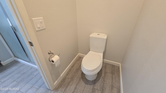 bathroom with baseboards, toilet, and wood finished floors