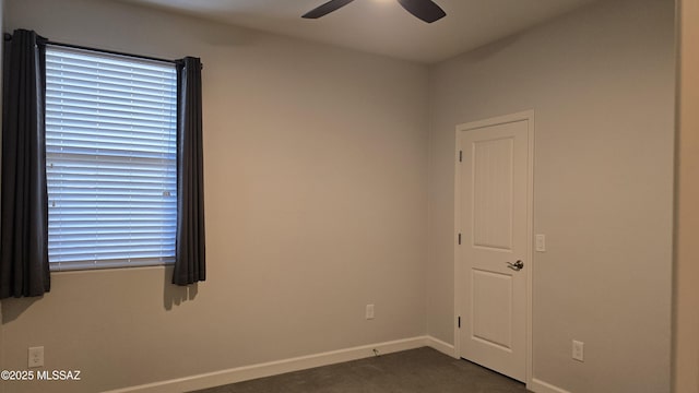 empty room featuring dark carpet, baseboards, and a ceiling fan