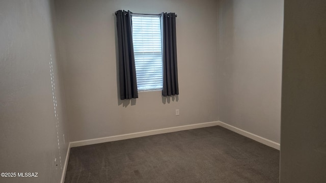 unfurnished room featuring dark carpet, baseboards, and a wealth of natural light