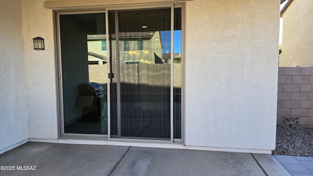 doorway to property featuring a patio, stucco siding, and fence