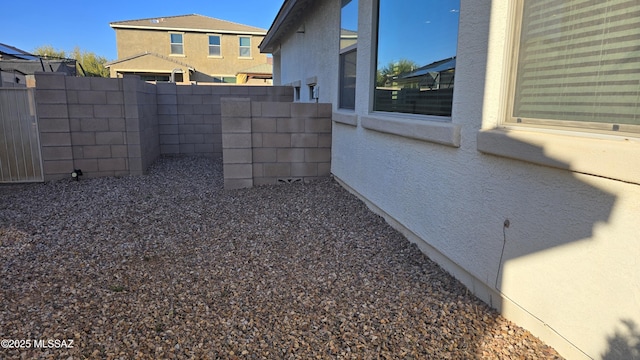 view of side of home featuring a fenced backyard and stucco siding