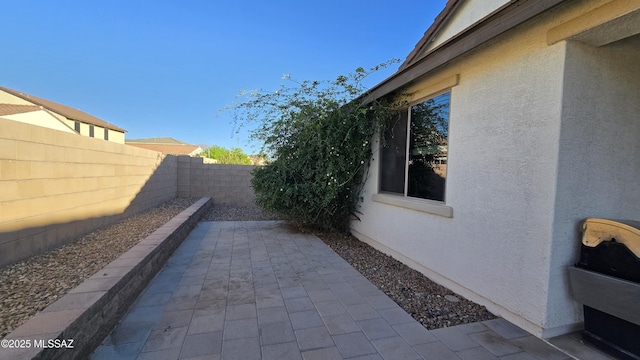 view of side of property with a fenced backyard, stucco siding, and a patio area