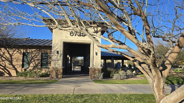 doorway to property featuring metal roof, stucco siding, a standing seam roof, and a gate