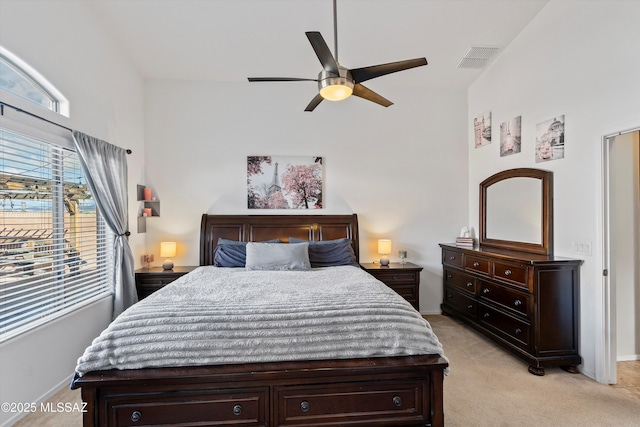 bedroom with light carpet, ceiling fan, visible vents, and baseboards