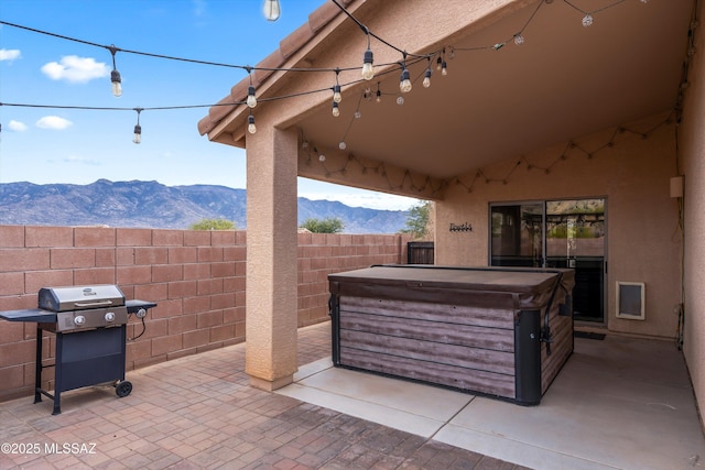 view of patio / terrace with a grill, fence, a mountain view, and a hot tub