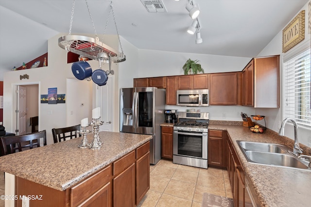 kitchen with visible vents, appliances with stainless steel finishes, vaulted ceiling, a sink, and a kitchen island