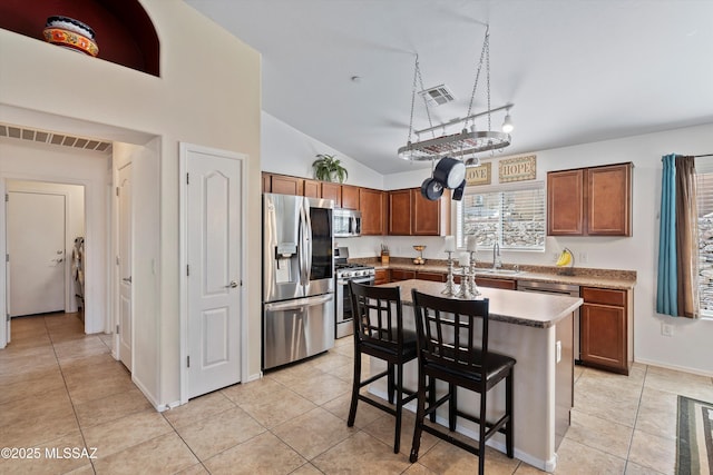 kitchen featuring stainless steel appliances, a breakfast bar, a kitchen island, and visible vents