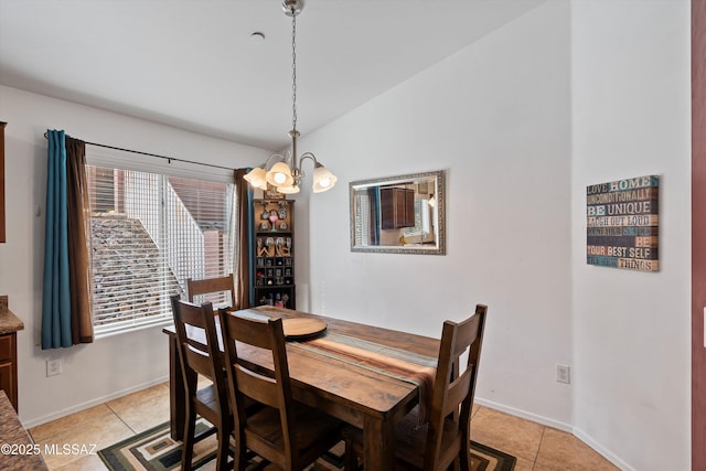 dining area with baseboards, a chandelier, vaulted ceiling, and light tile patterned flooring