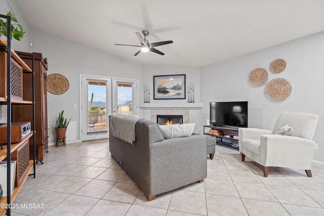 living room with a tile fireplace, ceiling fan, vaulted ceiling, and light tile patterned floors