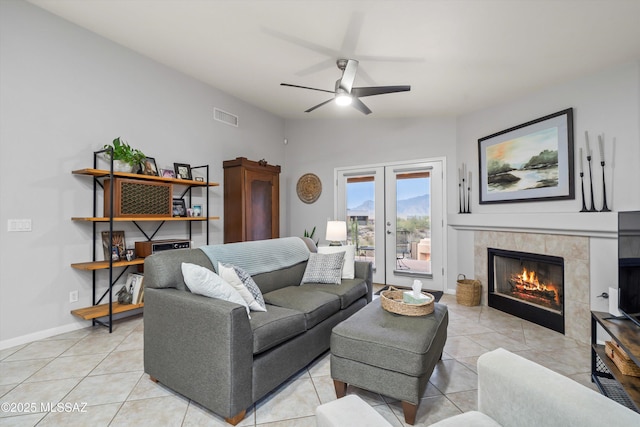 living room with visible vents, light tile patterned floors, a ceiling fan, a fireplace, and french doors