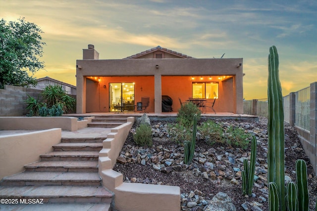 rear view of house featuring a patio area, a fenced backyard, a chimney, and stucco siding
