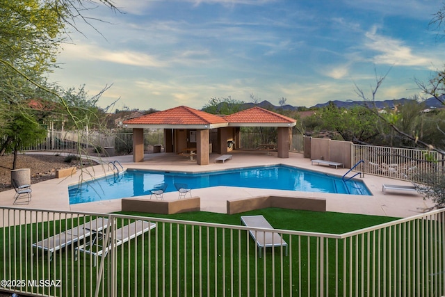 community pool featuring a mountain view, a patio area, a gazebo, a lawn, and fence