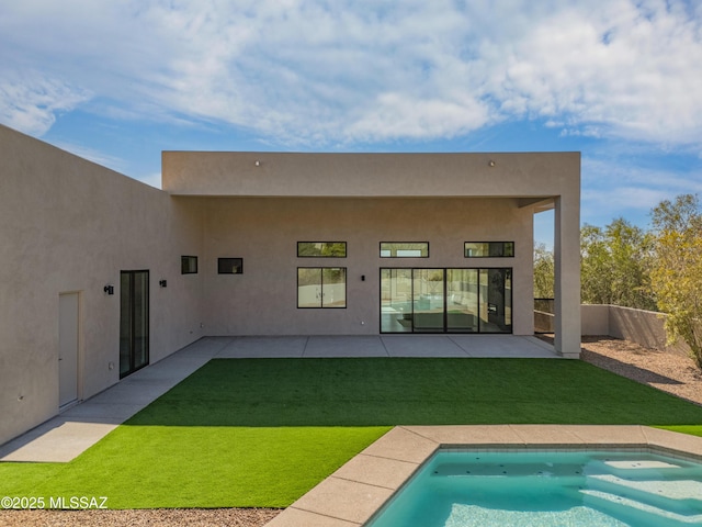 back of property with a fenced in pool, a patio, and a lawn