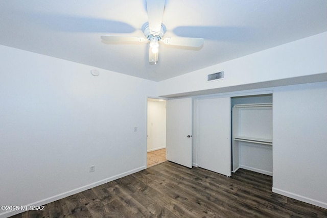 unfurnished bedroom featuring a closet, visible vents, baseboards, wood finished floors, and a ceiling fan