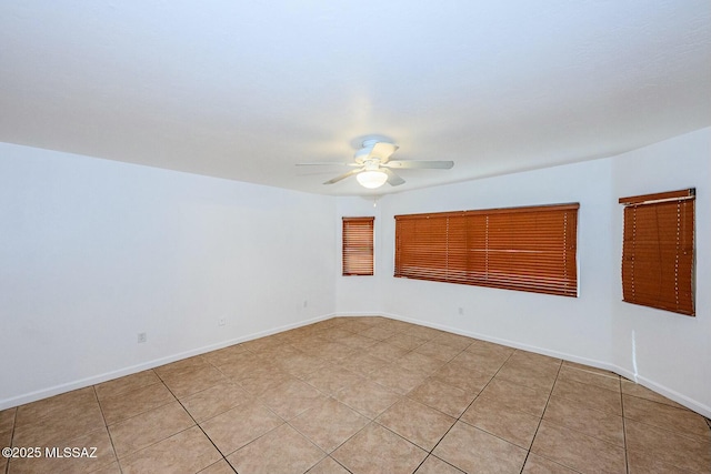 spare room featuring light tile patterned flooring, baseboards, and ceiling fan
