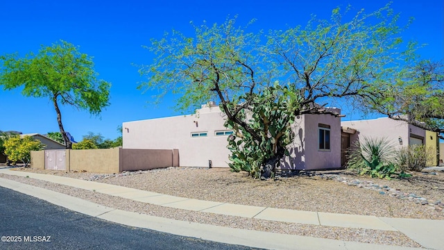 view of side of property with stucco siding and fence