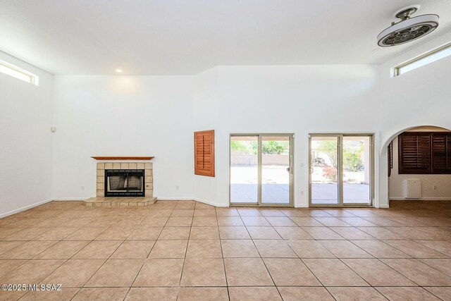 unfurnished living room with light tile patterned floors, a tile fireplace, and a wealth of natural light